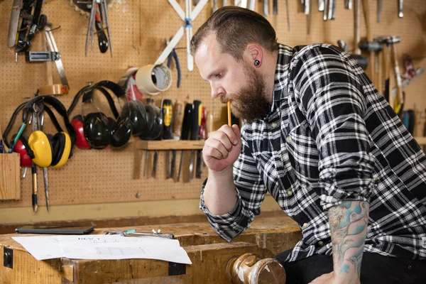 Timmerman planning van werkzaamheden en kijken naar tekeningen in de werkplaats — Stockfoto