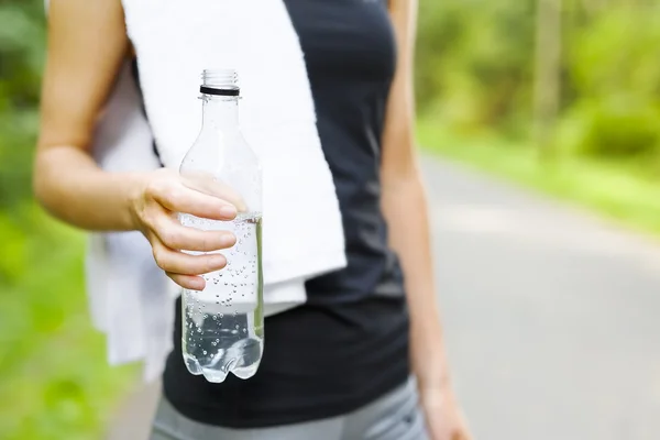 Woman stands outdoor and drinks water after workout — Stock Photo, Image