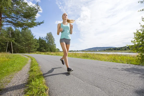 Мотивированная женщина быстро бегает по дороге в лесу — стоковое фото