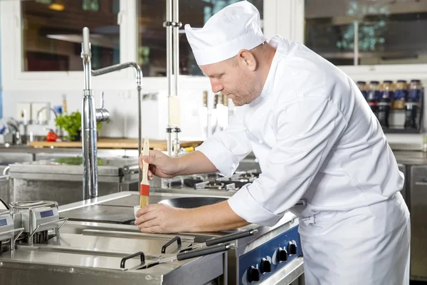 Chef using brush to prepare a dish in the kitchen — Stock Photo, Image