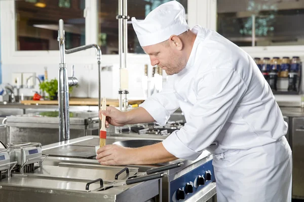 Chef utilisant une brosse pour préparer un plat dans la cuisine — Photo