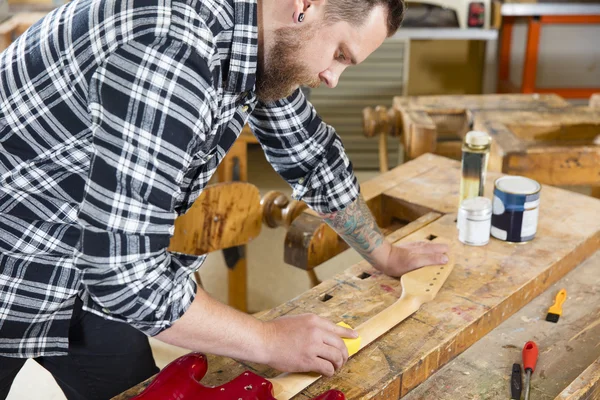 Ambachtsman schuren een gitaar hals in hout op workshop — Stockfoto