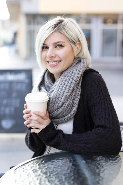 Lächelnde blonde Frau trinkt Kaffee im Freien im Café — Stockfoto