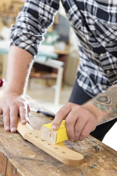 Carpintero lijando un cuello de guitarra en madera en el taller — Foto de Stock