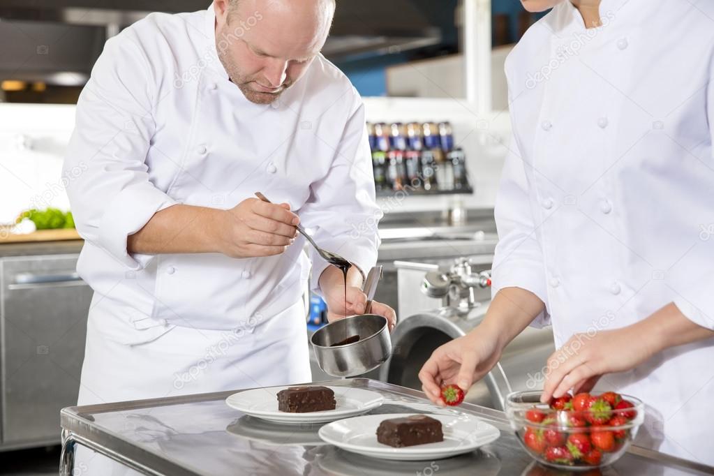 Chef decorates dessert cake with chocolate sauce in kitchen