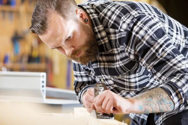 Werk met vliegtuig op houten plank in werkplaats timmerman — Stockfoto