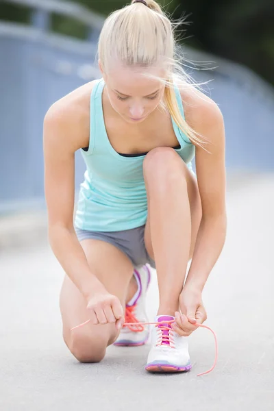スリムな女性ランナーの靴ひもを結ぶ橋の上 — ストック写真
