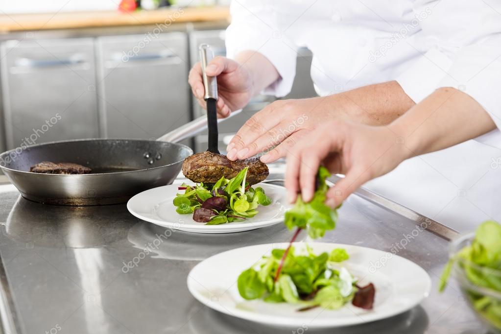 Professional chefs prepares steak dishes at restaurant