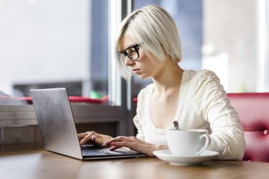 Genç kafede dizüstü bilgisayar ile çalışan kadın odaklı