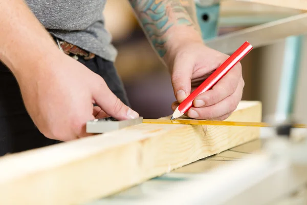 Carpinteiro mede o comprimento de uma prancha de madeira antes de serrar — Fotografia de Stock