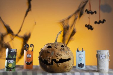 Bir balkabağı ve turuncu gökyüzünün önünde üç yarasalı dört küçük canavar.