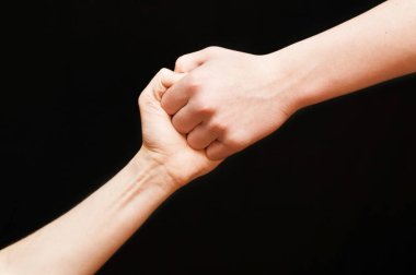 Jest, yardım ve umut işareti. Bir el diğer elini siyah arka planda tutuyor. Yatay olarak. El konseptine yardımcı oluyor