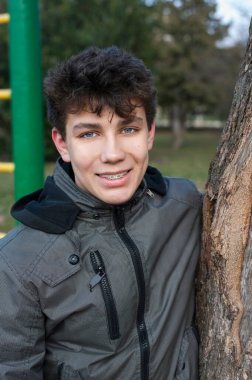 İyi bir ruh hali içindeki bir genç baharın başında sokakta antrenman yaptıktan sonra gülümser ve dinlenir. Dişlerini düzeltmek için diş telleri takılı. Dikey