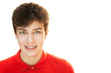 Beyaz arka planda siyah saçlı, kırmızı tişörtlü hoş bir adam. Gülümsüyor, dişlerinde diş teli var. Diş konsepti. İzole edilmiş