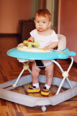 Evdeki küçük çocuk Bebek Yürüyüşçüleri 'nde. Yürümeyi öğreniyor. Dikey