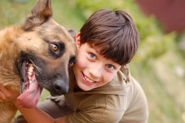 Счастливый Мальчик Улыбается Обнимает Большую Собаку Немецкую Овчарку Мальчик Любит Лицензионные Стоковые Изображения