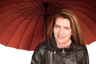 Deri ceketli, elinde şemsiyesi olan güzel bir kadın gülümsüyor. Yatay