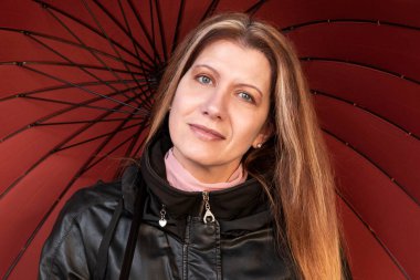 Güzel bir kadın, elinde şemsiyesi olan, sıcak ceketli, sakin, neşeli bir yüzü var. Kadın hava değişikliğine, sonbahara ve bahar yağmurlarına hazır olduğu için mutlu.