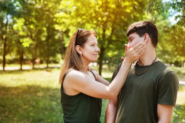 Bir kadın yetişkin ergen oğlunun söylediği saçmalıkları dinleyemez ve sanki bir kadın oğluna emir veriyormuş gibi ona vurmakla tehdit ettiğini gösterir ve gülümser. Anne ve oğul konuşuyor.