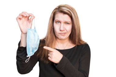 Beyaz arka plandaki bir kadın elinde tıbbi bir maske tutuyor ve üzerinde parmağını gösteriyor. Üşüttüğü ve evde tıbbi maske takması gerektiği için kadın memnun değil. 