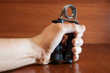 Elleri metali plastik saplı, elle genişletmeli tahta arka planda sıkıştırıyor. Güç kavramı, erkek cesareti.