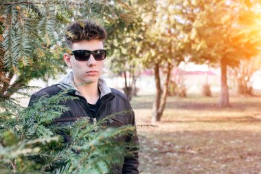 Genç yaşta gözlüklü bir adam parkta tek başına dinleniyor. Çocuk, arkadaşları olmadığı için üzgün. Boşluğu kopyala