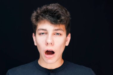 Ergenlik çağındaki bir çocuk yorgun ve siyah bir arka planda esniyor, gerçekten uyumak istiyor. O, okulda çalışmaktan bıkmıştı. Uzayı kopyala Yatay