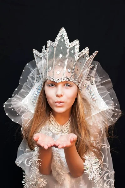 Kafasında taç olan Kar Kraliçesi kostümü giyen kız havada öpüşüyor. Dikey