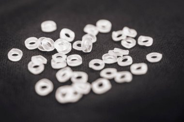 Diş konsepti. Dişleri hizalayan diş telleri için elastik bantlar siyah bir kumaşın üzerinde yatar.