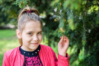 Genç kız bahara çok düşkün ve onu dört gözle bekliyor, şimdi sıcak havalarda her ağacın yanında fotoğraf çekiliyor. Çam ağacının yanındaki genç kızın portresi. Bahar geldi.
