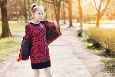 Kız ceketi çıkarır çünkü cadde çok sıcaktır. Genç kız baharı seviyor, gülümsüyor.