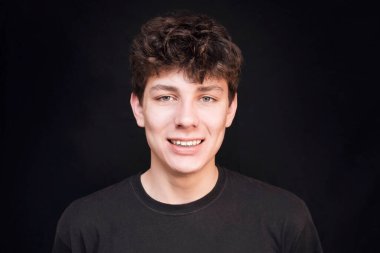 Siyah gömlekli yakışıklı bir adam siyah arka planda gülümsüyor. Adamın alt çenesinde diş telleri var. Diş Konsepti