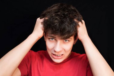 Siyah arka planda kırmızı tişörtlü bir çocuk dişlerinde diş teli olduğu için baş ağrısından muzdarip. Tıbbi konsept