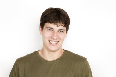 Açık arkaplanda genç bir adamın portresi, koyu renk saçlı ve beyaz dişli bir haki gömlekli adam gülümsüyor. Adam üniversitede bir sürü arkadaşı olduğu için mutlu.