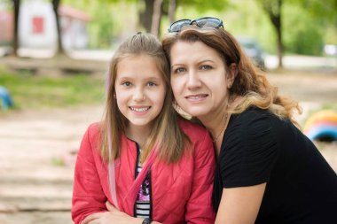 Mutlu kadın güzel kızına sarılıyor ve ikisi de gülümsüyor çünkü hepsi iyi. Kızı ve annesi en iyi kız arkadaşlar.