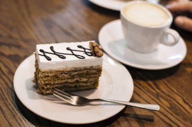 Fındıklı, kremalı ve çikolatalı enfes bir pasta. Kafedeki masada kapuçinonun yanında. Kahve için lezzetli atıştırmalıklar.