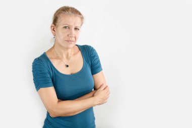 Hafif arka planda, basit giysiler içinde olgun bir kadın gülümsüyor, biraz yorgun ama mutlu, tatmin olmuş, işi ve iyi bir ailesi olduğu için mutlu, saçları şimdiden ağarmaya başladı, saçını boyama zamanı.