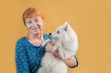 Mutlu emekli kadın köpeğini kollarında tutuyor, onunla konuşuyor ve gülüyor, evcil hayvan yaşlı kadını daha az yalnız, daha sağlıklı ve daha mutlu yapıyor, kadın köpek sayesinde yürüyor..