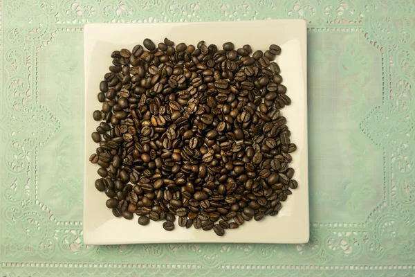Piatto quadrato bianco con un mucchio di chicchi di caffè — Foto Stock