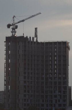 İnşaat alanı. Yüksek bina inşaatı. Bulutlu bir gökyüzünün arka planında bir vinç.