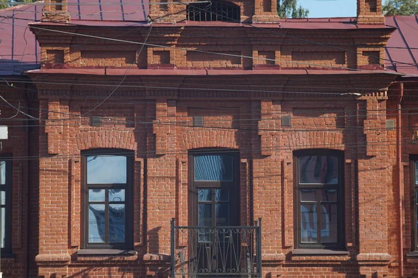 古代の建物のファサードの一部の写真 建築的要素とのレンガ造り 屋根は赤い鉄で覆われている バルコニーの錬鉄製の格子 — ストック写真