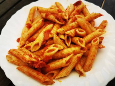 domatesli makarna ve ahşap masada maydanoz. Domates soslu makarna, taze fesleğen ve kızarmış domates.