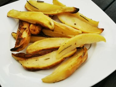 Tahta bir arka planda beyaz yuvarlak tabakta leziz sarı patates turtaları.