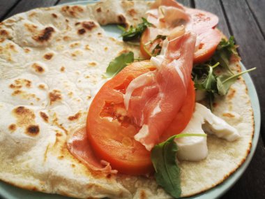 Mozzarella peynirli, domatesli, jambonlu ve roket salatalı Piadina Romagnola..