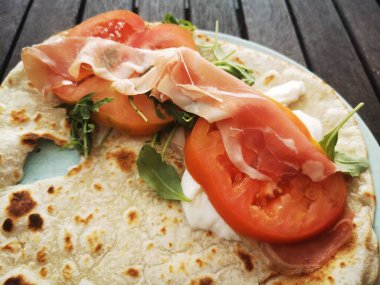 Mozzarella peynirli, domatesli, jambonlu ve roket salatalı Piadina Romagnola..
