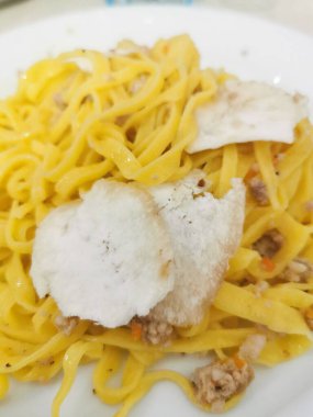 A delicious plate of fresh tagliolini pasta topped with savory minced meat and delicate slices of white truffle.