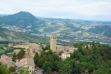 Montefeltro 'nun yumuşak, dalgalı tepeleri tarafından çerçevelenmiş kayalık uçurumuna tünemiş geniş bir San Leo manzarası.