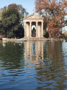 ROMA, ITALIA - DIC 7 - 2025: Bu çarpıcı görüntü, Roma 'nın Villa Borghese kentindeki sakin göl üzerindeki Aesculapius Tapınağı' nı yakalar..