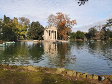 ROMA, ITALIA - DIC 7 - 2025: Bu çarpıcı görüntü, Roma 'nın Villa Borghese kentindeki sakin göl üzerindeki Aesculapius Tapınağı' nı yakalar..