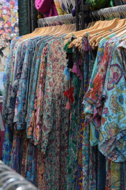 Bir market tezgahında sergilenen renkli geleneksel giysi askısı. Kırmızı, mavi, yeşil ve siyah işlemeli kumaşlar. Karmaşık altın işlemeli ve zarif dokular..